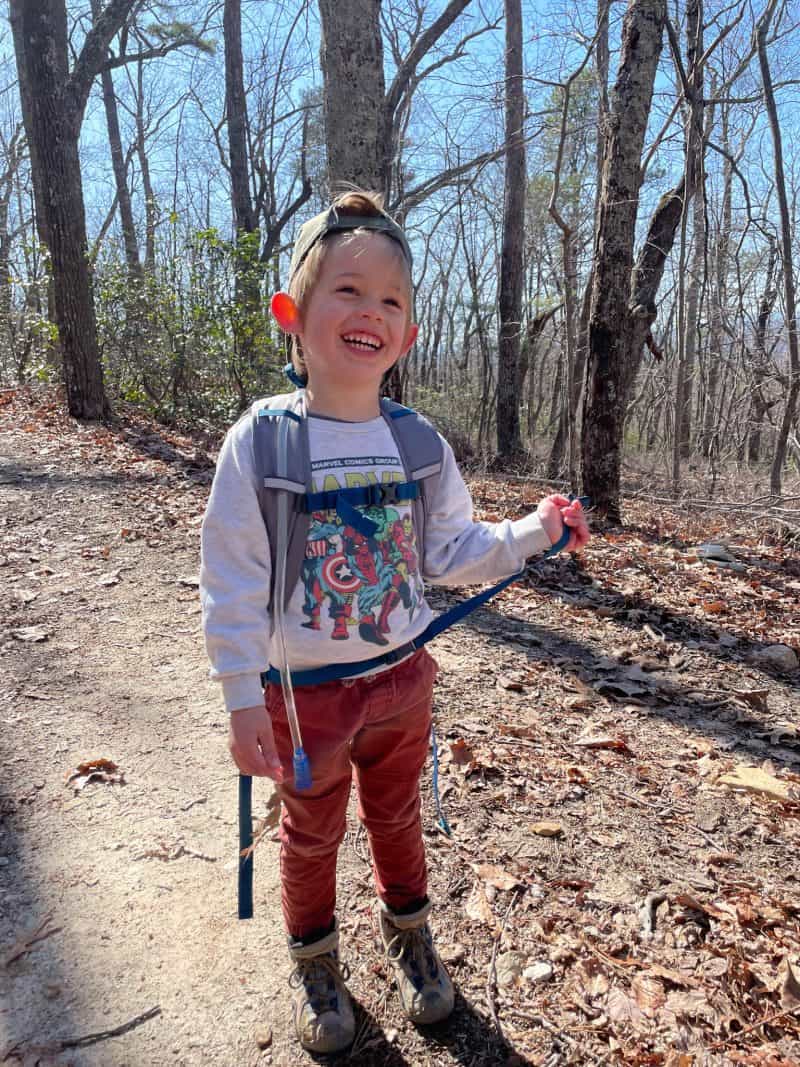 child hiking in the woods smiling